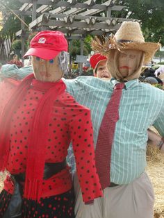 two scarecrows wearing hats and scarves at an outdoor event