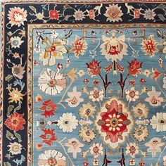 a blue and red rug with many flowers on it's border, in the middle