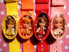 three little dolls are sitting in small oval clocks