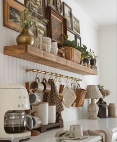 a kitchen counter with pots, pans and coffee cups hanging on the wall above it