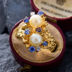 a close up of a ring with pearls and sapphires on it in a box