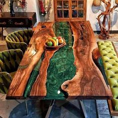 a wooden table with green chairs and a bowl of fruit on the center piece in front of it