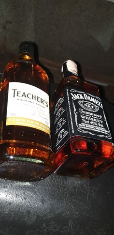 two bottles of whiskey sitting on top of a table next to each other, one containing an empty bottle