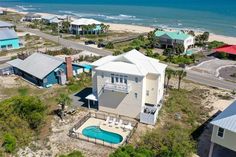 an aerial view of a beachfront home with a swimming pool in the foreground