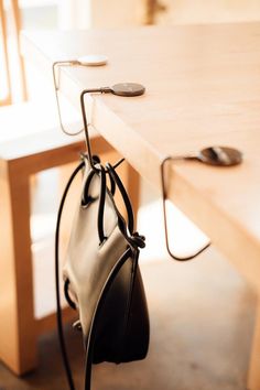 a purse hanging from the side of a wooden table