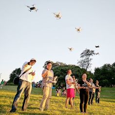 a group of people standing on top of a lush green field flying kites in the sky