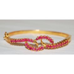 5-micron plated base metal with ruby stones. Formal Pink Ruby Bracelets, Formal Pink Ruby Bracelet, Red Ruby Bangle As Gift, Adjustable Yellow Gold Ruby Jewelry, Elegant Gold Bracelets With Ruby, Yellow Gold Ruby Bangle Bracelets, Elegant Gold Ruby Bracelets, Gold Ruby Bracelets For Formal Occasions, Ruby Bangle Bracelet In Yellow Gold