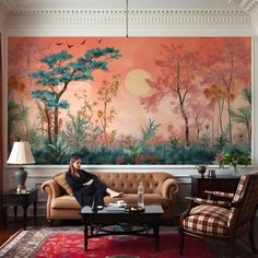 a woman sitting on top of a couch in front of a wall with trees painted on it