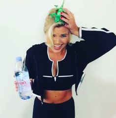 a woman with blonde hair holding a water bottle and wearing a black sports bra top