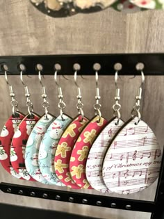 six christmas themed keychains hanging from hooks on a rack with sheet music notes