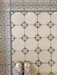 a pair of shoes sitting on top of a tiled floor next to a wall with blue and white tiles