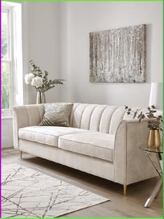 a living room with a white couch, rug and painting on the wall above it