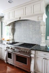 a large kitchen with white cabinets and stainless steel stove top oven in the center island