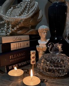 some candles are sitting on a table next to books and other items in front of them