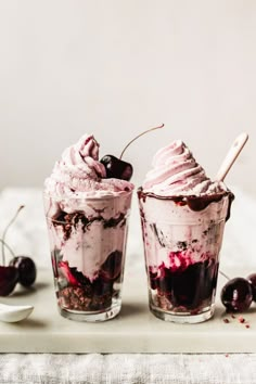 two glasses filled with ice cream and cherries