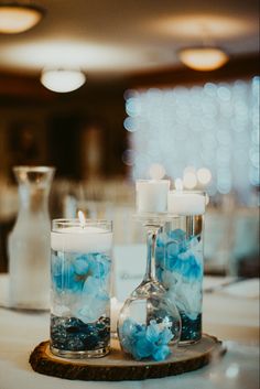 two vases filled with blue flowers on top of a wooden tray next to candles