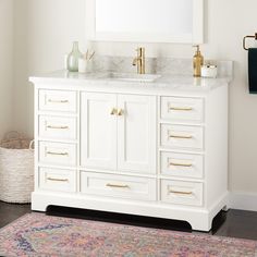 a white bathroom vanity with two sinks and gold faucets on the counter top