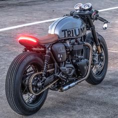 a triumph motorcycle parked on the street with it's brake lights turned on,