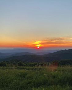 the sun is setting over mountains in the distance