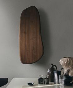 a wooden shelf hanging from the side of a wall next to cups and vases