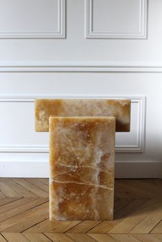 a marble block sitting on top of a hard wood floor next to a white wall