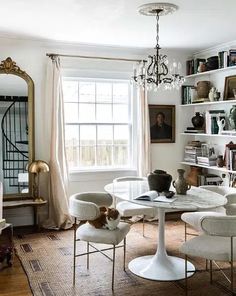 a living room filled with furniture and a cat sitting on top of a table in front of a window