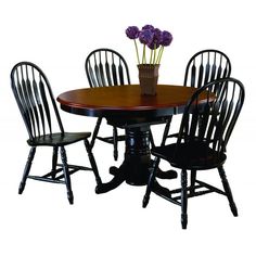 a wooden table with four chairs around it and a vase filled with flowers on top