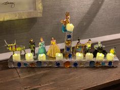 a group of figurines sitting on top of a wooden table next to candles