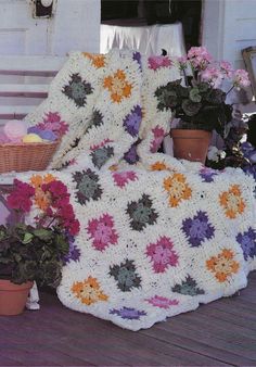 there is a crocheted blanket and potted plants on the porch