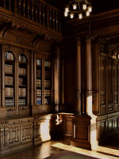 an empty room with wooden bookshelves and chandelier