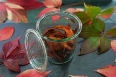 a glass jar filled with dried leaves on top of a blue cloth covered tablecloth