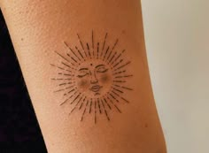 a woman's arm with a small sun tattoo on the back of her left arm