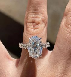 a woman's hand with a diamond ring on top of her finger and an engagement band