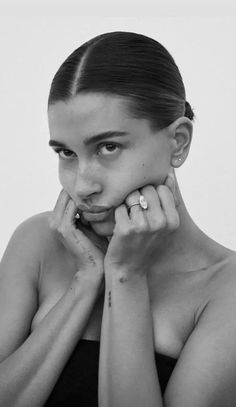 a black and white photo of a woman holding her hand to her face while looking at the camera