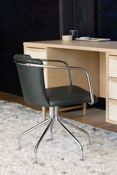 a black office chair sitting on top of a white rug next to a wooden desk