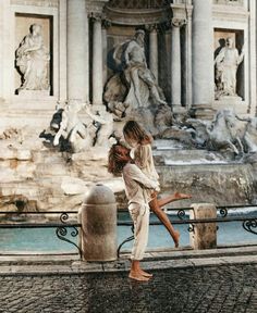 two people are kissing in front of a fountain