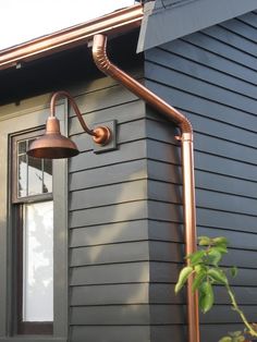 an outdoor light on the side of a house next to a window with a hose coming out of it