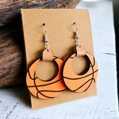 the hoop earrings are made out of wood and have an orange basketball design on it