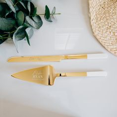 two gold and white utensils sitting on top of a table next to a straw hat