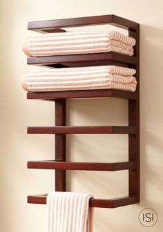 the towel rack is made out of wood and holds three folded towels, one hanging on it