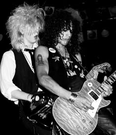 two people are playing guitars together in black and white