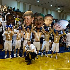 a group of people holding up signs in front of them on a basketball court with the faces of two men and one woman