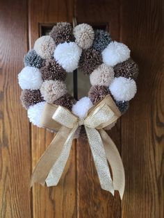 a wreath with pom - poms hanging on the front door