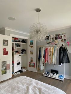 a bedroom with white closets and clothes hanging on the wall next to a bed