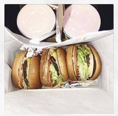 three large sandwiches in a box next to two plates