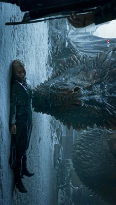 a woman standing next to a giant dragon in a dark room with snow on the ground