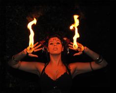 a woman holding two torches in her hands with flames coming out of the top of her head