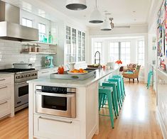 a kitchen with white walls and wooden floors has blue stools on the countertop