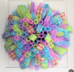 a wreath made out of plastic tubes and streamers on the front door, decorated with colorful paper straws