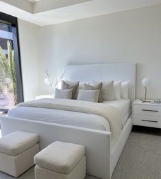 a large white bed sitting in a bedroom next to a window